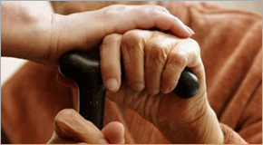 Comforting hand on top of an elder hand on a cane.