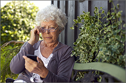 Grandmother sitting on a bench looking at her cell phone.