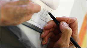 Hand with a pen signing a check.