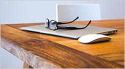 Desk with laptop, mouse, and glasses